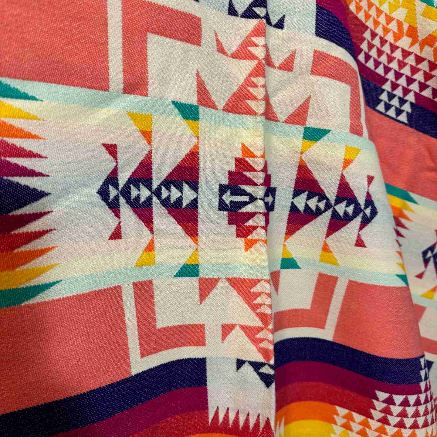 Close-up of orange and multicolor patchwork geometric pattern on Cactus Bloom Fiesta poncho